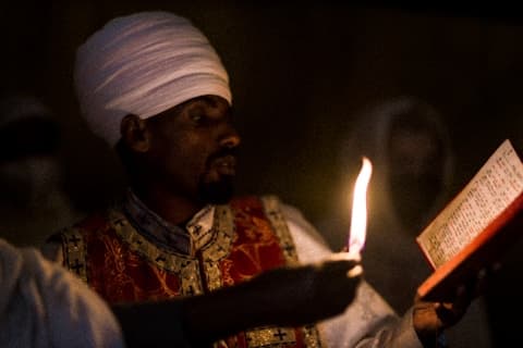 A priest holding a lit candle