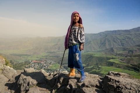 A girl standing on the escarpment above a highland town